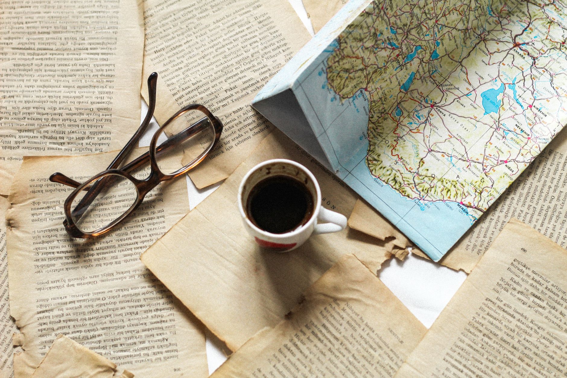 Travel author reviewing map and field notes at an old wooden desk